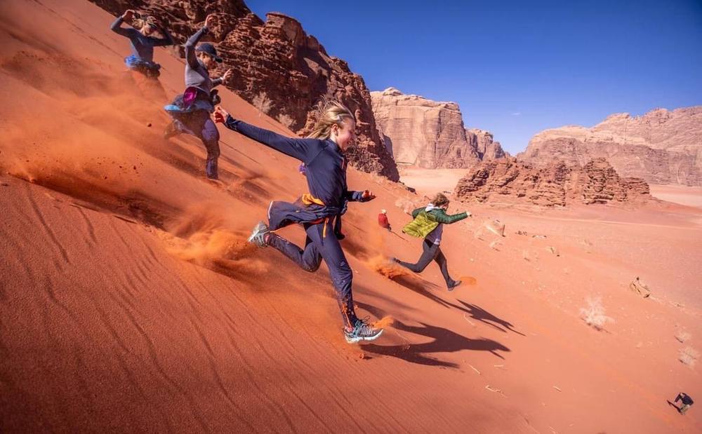 Children running down a red sand dune