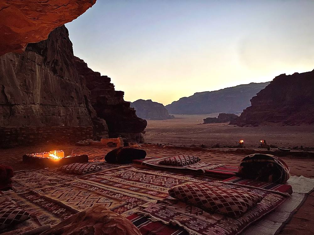 Falcon Nest Cave with rugs and a fire overlooking the desert at dusk